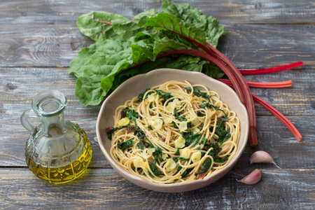 Vegan spaghetti with chard and garlic on a wooden table. Delicious homemade foodの写真素材