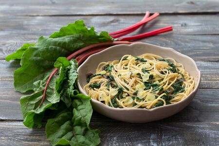 Vegan spaghetti with chard and garlic on a wooden table. Delicious homemade foodの写真素材