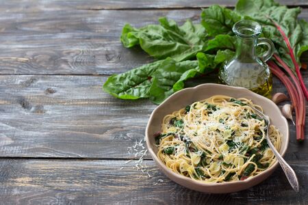 Delicious spaghetti with chard, garlic and cheese on a wooden table. Simple homemade foodの写真素材