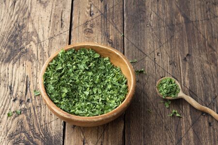 Dried green celery in a wooden bowl on a wooden table, top view, free spaceの写真素材