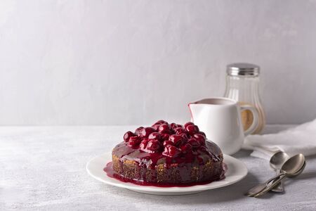 Delicious homemade chocolate pie with cherry sauce, with fresh cherry on a gray background, free spaceの写真素材