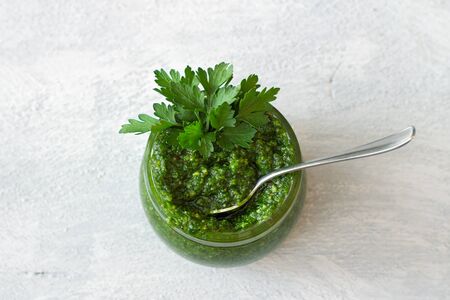 Fresh homemade parsley pesto with hazelnuts in glass jar on light gray background. delicious vegan foodの写真素材