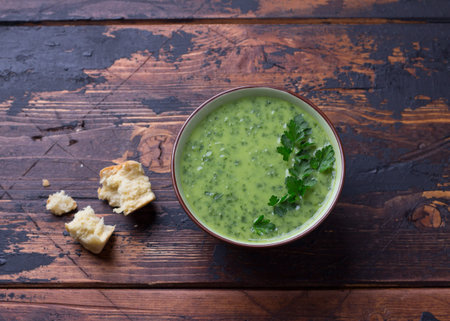 Healthy green kale potatoes cream soup and bread on wooden background. simple homemade foodの写真素材