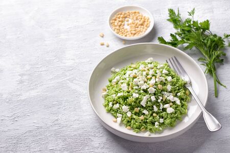 Vegan rice with green oil, pine nuts, cheese in a white bowl on a gray background, free space. delicious healthy homemade foodの写真素材