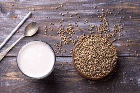 Hemp seeds in a wooden bowl and hemp milk on a wooden background. superfood, healthy natural vegan foodの写真素材