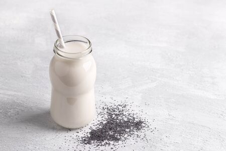 Fresh poppy milk in bottle with seeds on light background. healthy diet, vegan drink, alternative milk. free spaceの写真素材