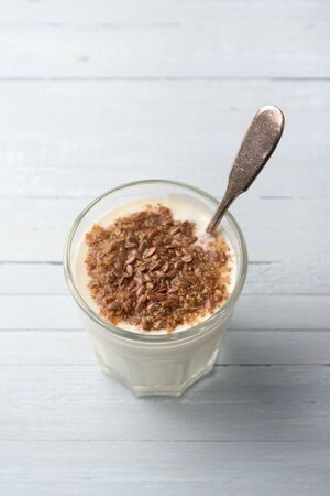 Simple healthy breakfast or snack. Natural yogurt with ground flax seeds in glasses on a light blue backgroundの写真素材