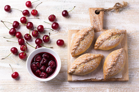 Sweet homemade baked mini pies with cherry and cinnamon on wooden backgroundの写真素材