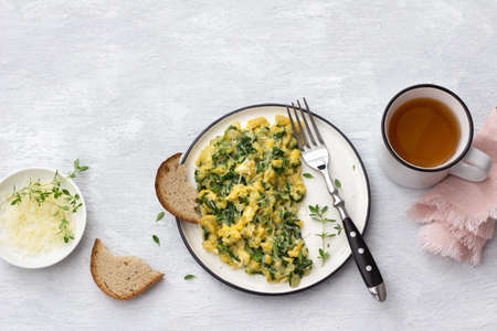 Scrumble eggs with kale and cheese on a light gray background, top view. delicious homemade breakfastの写真素材