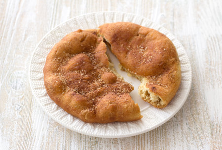 Homemade Navajo fried bread or sweet Elephant Ears with brown sugar and cinnamon on wooden table,...