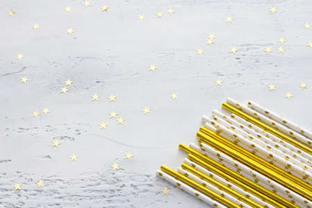 Festive drinking straws golden and white with golden stars for party on light gray background, flat lay, spaceの写真素材