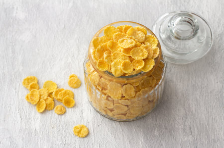 Sweet crunchy cornflakes in a glass jar on a gray textured background. Fast tasty breakfast, free space, horizontalの写真素材