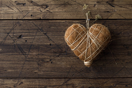 Straw heart hanging on a nail on a wooden wall, rustic style, spaceの写真素材