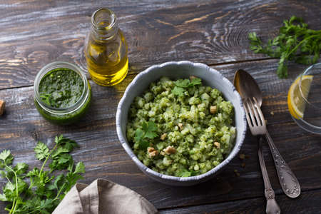 Homemade potatoes crumpled with pesto sauce, nuts, herbs and olive oil on a wooden table, top viewの写真素材