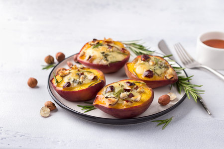 Baked peaches with blue cheese, hazelnuts, rosemary, served with honey on a light gray backgroundの写真素材