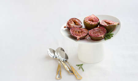Baked Figs with sugar muskovado and butter on white tablecloth with copy spaceの写真素材