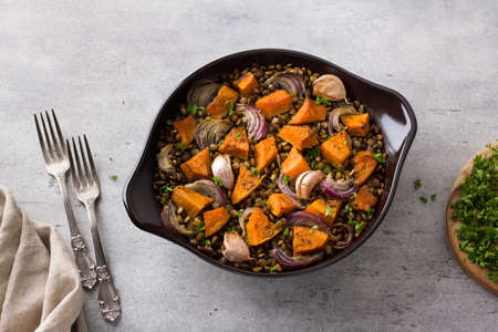 Baked lentils with pumpkin and onions in a ceramic mold on a gray textured background, top view. Delicious homemade foodの写真素材