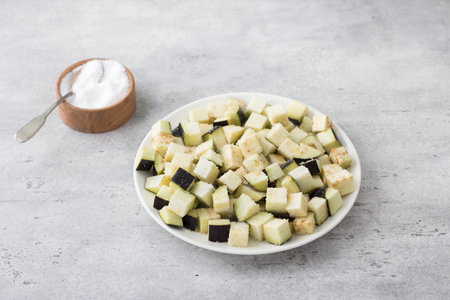 A plate of eggplant sprinkled with salt and a bowl of salt on a gray background. The concept of cooking vegan homemade foodの写真素材