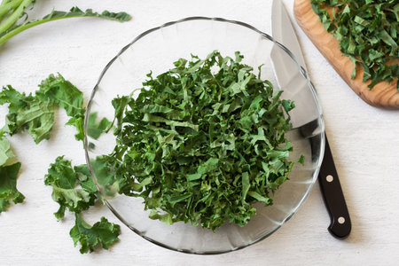 Chopped kale cabbage leaves, crushed with salt in a transparent bowl on a light gray background. Healthy detox foodの写真素材