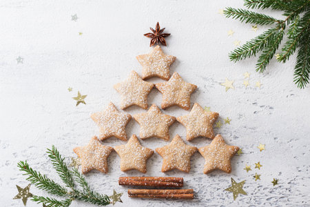 Christmas tree made of homemade gingerbread cookies in the shape of stars on a light blue background, top viewの写真素材
