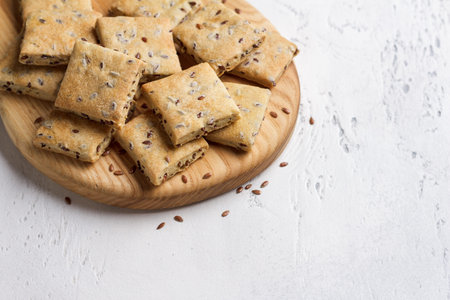 Homemade crunchy flaxseed crackers on wooden board, healthy snack with whole grain ingredients