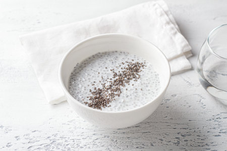 Healthy Chia Seed Pudding in White Bowl with Spoon and Dry Chia Seeds on Light Backgroundの写真素材