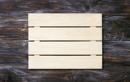 Light wooden pallet on dark rustic wood, blank signboard for designの写真素材