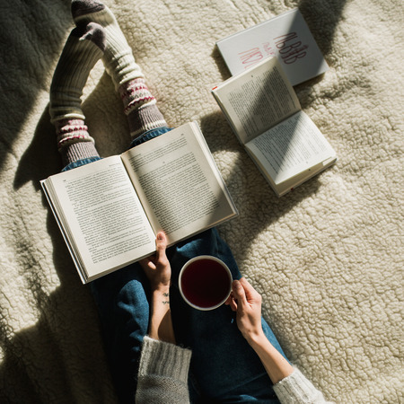 Feet in woollen socks. Woman relaxes with a cup of hot drink and warming up her feet in woollen socks. Close up on feet. Winter and Christmas holidays concept.の写真素材