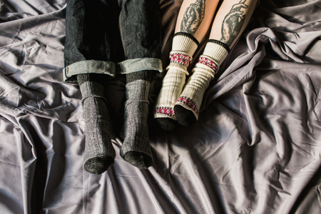 Feet in woollen. Pair relax with a cup of hot drink and warming up their feet in woollen socks.の写真素材