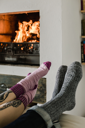 Feet in woollen. Pair relax with a cup of hot drink and warming up their feet in woollen socks.の写真素材