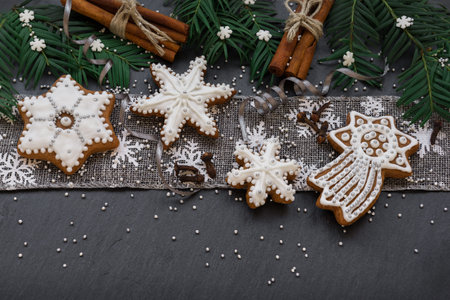 Frame with fir branches, cookies and Christmas decorations on dark stone background. Top view.