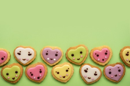 Heart shaped sugar cookies decorated with pastel royal icing on pink backgroundの写真素材