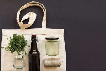 Cotton shopping bag, jar, bottle and cooking thread on a gray linen background