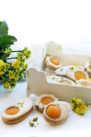 Happy Easter. Cookies in the shape of white eggs with apricot yolk with pistachios as homemade...