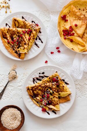 Thin Crepes with melted chocolate, sesame seeds, pomegranate and almonds. Top view. Tasty thin pancakesの写真素材