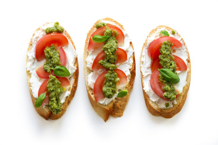 Toast with soft mascarpone cheese, tomatoes and fresh basil pesto. Top view, isolated on white...
