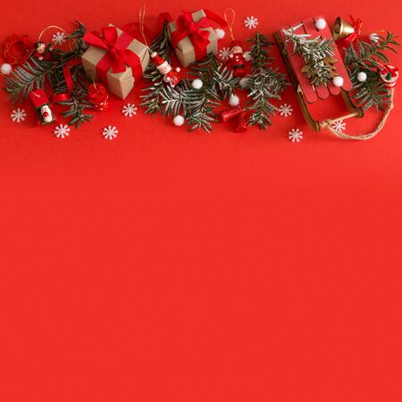 Christmas border of toys, gift box, ribbons and snowflakes on red background. Flat lay, top view, copy spaceの写真素材