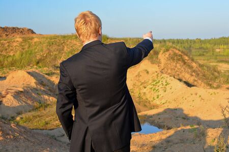 the man against a sandpit specifies by a hand in a distance in a jacketの写真素材