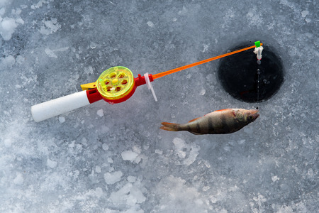 the rod for winter fishing lies near a holeの写真素材