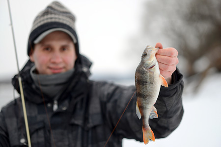 A man holding a fish caught in the winterの写真素材