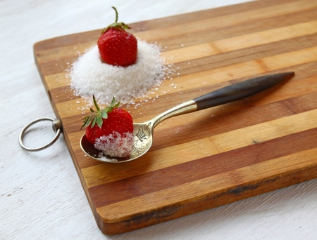 Spoon and delicious strawberry with sugar on wooden tableの写真素材