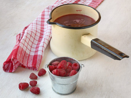Raspberry on a background of the saucepan with a compote on the tableの写真素材