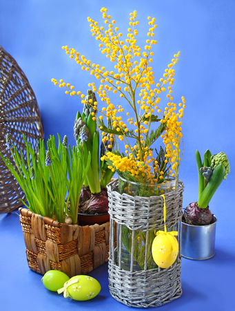 Easter still life with spring flowers and decorative eggs on a blue backgroundの写真素材