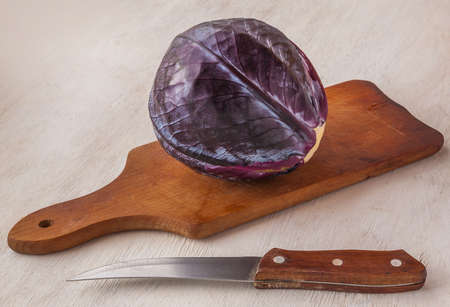 Fresh red cabbage head and knife out on a cutting boardの写真素材
