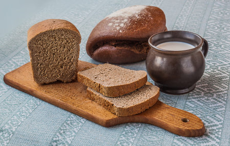 Mug with milk and rye bread on the tablecloth with Ukrainian embroidered pattern