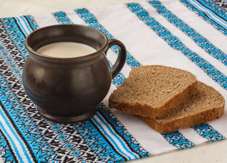 Mug with milk and rye bread on the tablecloth with Ukrainian embroidered patternの写真素材