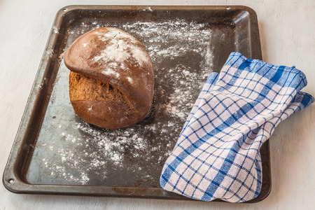Fresh rye bread on the French recipe on dripping pan and towel in a blue checkeredの写真素材