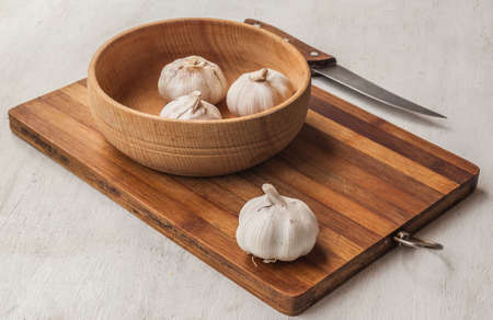 Garlic on a cutting board and garlic in a bowlの写真素材