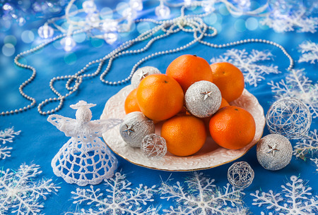 Plate with mandarin  and Christmas  knitted angel on a blue backgroundの写真素材