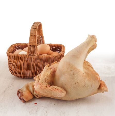 Raw chicken carcass home on the background basket with eggs on the kitchen tableの写真素材